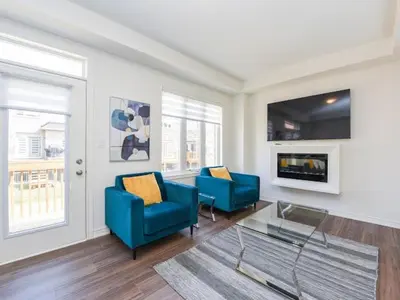 a living room with two blue chairs and a tv at Stylish Home in Waterdown in Hamilton
