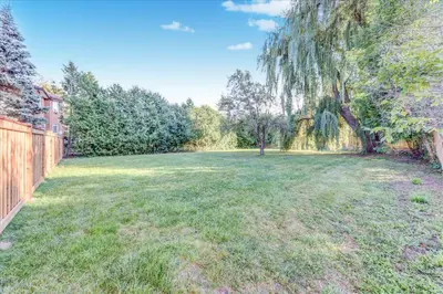 a large yard with a fence and a tree at Stunning 7 Br RougeView Home with 2 Kitchens, 5 Bathrooms, Amazing Backyard & 8-Car Parking in Toronto