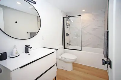 a bathroom with a sink and a toilet and a mirror at Sherkston Bliss - Hot Tub Soaks & Backyard BBQ Fun in Port Colborne