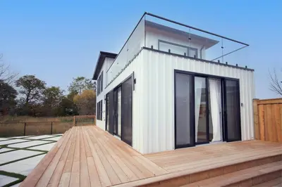 a house on a wooden deck with glass windows at Sherkston Bliss - Hot Tub Soaks & Backyard BBQ Fun in Port Colborne