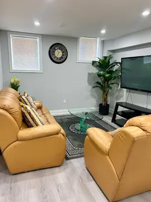 a living room with two chairs and a flat screen tv at SUITE A 2 Bedroom Apartment in Brampton