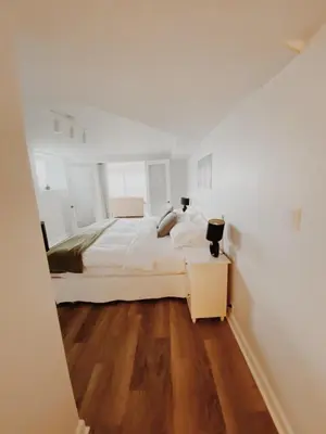 a white bedroom with a large bed and a wooden floor at Irish Mountain Suites in Meaford