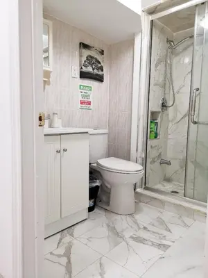 a white bathroom with a toilet and a shower at Tidy Private Rooms with Full Kitchen in Toronto