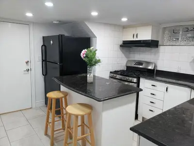 a kitchen with a black refrigerator and two bar stools at Tidy Private Rooms with Full Kitchen in Toronto