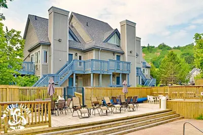 a large house with a deck with chairs at Mountainview Loft at North Creek Resort in Blue Mountains