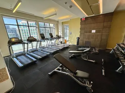 a gym with a row of treadmills and chairs at The Vine & View Suite in Toronto