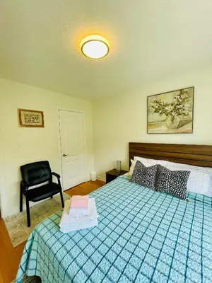 a bedroom with a bed and a black chair at Homestay- private room and bathroom in Whitby