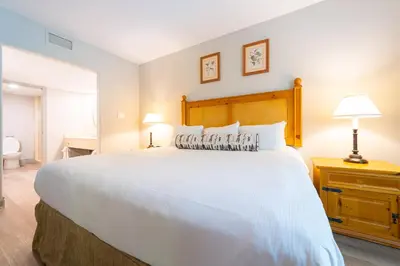 a bedroom with a large white bed with a wooden headboard at Horseshoe Valley Suites - The Evergreen in Shanty Bay