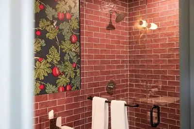 a bathroom with a tile shower with two towels at The Dorchester Hotel in Collingwood