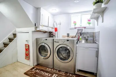 a laundry room with two washing machines and a sink at 2 Bedroom East-York bungalow in Toronto