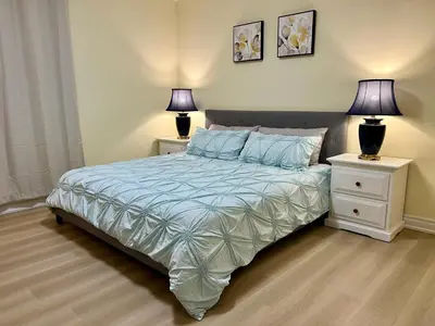 a bedroom with a bed with two night stands and two lamps at Two-bedroom Suite with King Bed-4 Minutes to The Falls in Niagara Falls