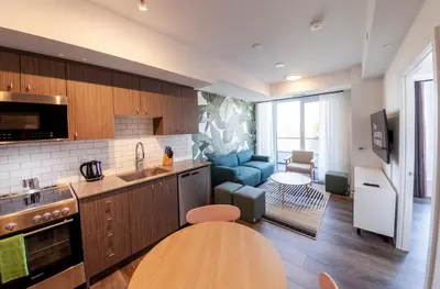 a kitchen with a table and a living room at The Laundry Rooms Station Park Kitchener in Kitchener