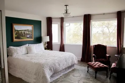 a bedroom with a bed and a chair and windows at Waterfront Boutique Accommodation in PEC - Suite 3 in Belleville