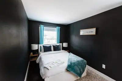 a bedroom with a large bed with black walls at Hamilton's Beach House Stunning Lake Views! Modern Open concept HotTub,firepit, 3BR in Hamilton
