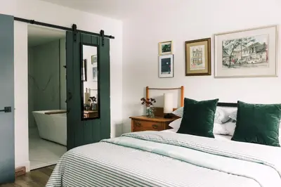 a bedroom with a bed and a bathroom with a tub at The Old Homestead - Gorgeous backyard right in The Heart of Picton in Picton