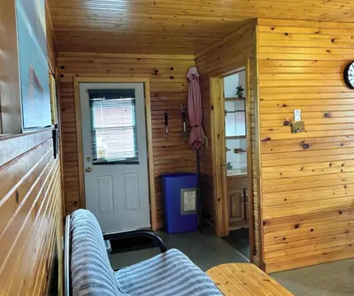 a room with wooden walls and a door and a couch at Sandy Shore Cottages Luxury Resort on Rice Lake in Harwood