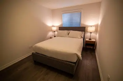 a bedroom with a bed with two lamps on it at Modern & Cozy Retreat Lake Ontario & Wine Country in Grimsby