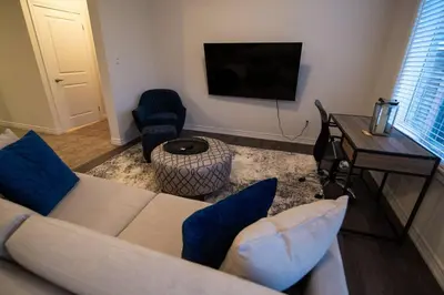 a living room with a couch and a table and a television at Modern & Cozy Retreat Lake Ontario & Wine Country in Grimsby