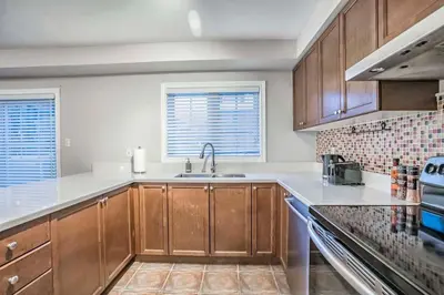 a kitchen with wooden cabinets and a sink at Stylish 4BR Home 20 Mins from YYZ in Mississauga