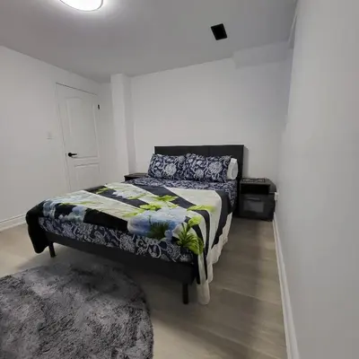 a bedroom with a bed and a rug at Bright 2 Bedroom Basement Apartment in Angus in Angus