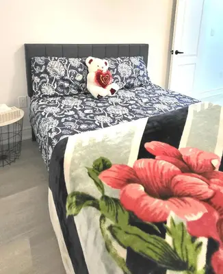 a teddy bear sitting on a bed in a bedroom at Bright 2 Bedroom Basement Apartment in Angus in Angus