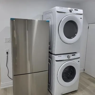a refrigerator and a washer and dryer in a room at Bright 2 Bedroom Basement Apartment in Angus in Angus