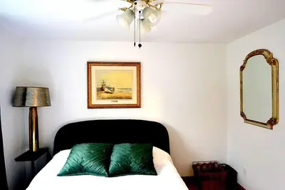 a bedroom with a bed with a green pillow on it at Cellar House NOTL - Entire Home in the Heart of Niagara-on-the-Lake in Niagara on the Lake