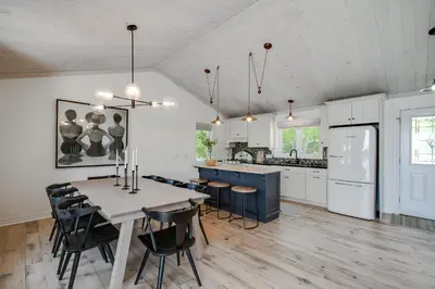 a kitchen with a table and chairs and a kitchen with white cabinets at Lakefront Retreat Hot Tub Outdoor Sauna Dock Swim Stunning Views! in Rosseau