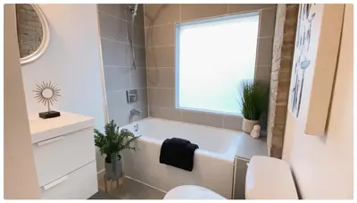 a bathroom with a tub and a toilet and a window at Cozy Place on Main Floor in Toronto