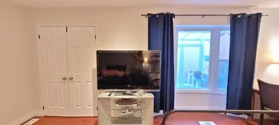 a living room with a tv and blue curtains at Toronto Spacious Cozy Mainfloor Room in Toronto