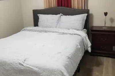 a bed with a white comforter and a night stand at Cozy Luxurious Detached 4 Bedroom House in Guelph