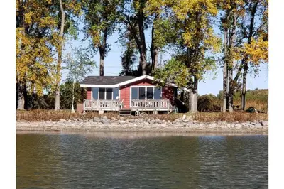 a red house on the shore of a body of water at West Lake Waterfront Swimming - Free Pontoon Boat! in West Lake
