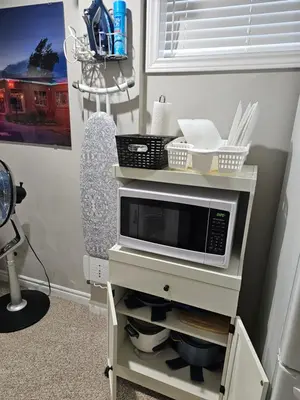 a microwave on a stand with a chair in a room at Amazing cozy fully private studio in London