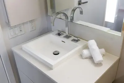 a white bathroom with a sink and a mirror at Downtown Charm 2BR Retreat in Prime Location in Toronto