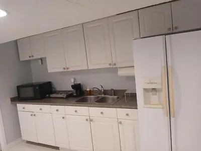 a kitchen with white cabinets and a sink and a refrigerator at Furnished calm basement studio apartment in Mississauga