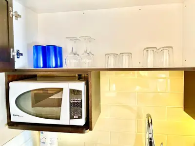 a microwave in a kitchen with glasses on a shelf at Hillside Haven: Carriage Club Resort Retreat in Edgar
