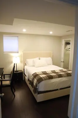a bedroom with a bed and a table and a lamp at Stunning Furnished 2 Bedroom 2 Washroom Basement Apartment in Brampton