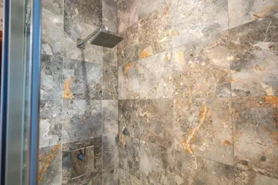 a bathroom with a shower with a stone wall at Vineyard Villa in Niagara on the Lake