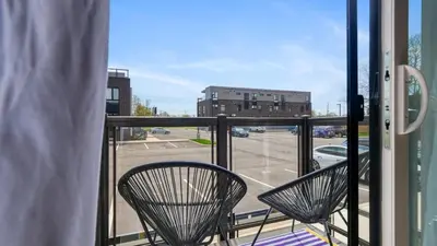 two chairs on a balcony with a view of a parking lot at 2br Boho Townhouse - Walk To Falls, Free Parking in Niagara Falls