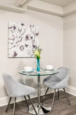 a dining room table with two chairs and a vase with flowers at Modern Apartment in a Trendy Neighbourhood in Hamilton