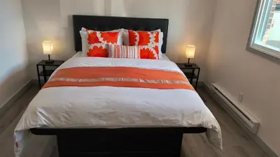 a bed with orange and white sheets and two lamps at SHORE VISTA LODGE in Georgina