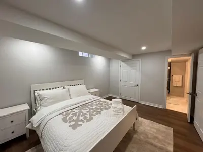 a bedroom with a large white bed and a bathroom at Spacious Bottom-Floor 2BR Suite in Innisfil