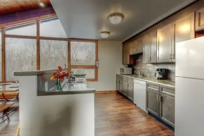 a kitchen with stainless steel appliances and wooden cabinets at 8 bdrm Blue Mountain Cottage, Large Groups, Private Beach Access, Hot Tub, Sauna, Ping Pong Table Perfect for Large Groups, Petfriendly in Blue Mountains