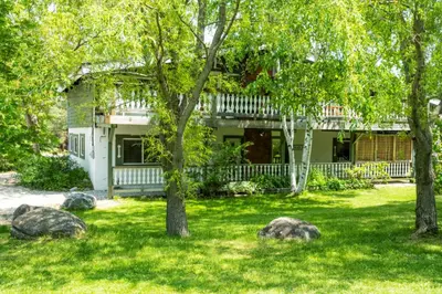 a house with trees and rocks in the yard at 4 Bedroom Cottage near The Village, Private Beach Access, BBQ, Petfriendly in Blue Mountains