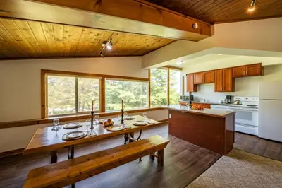 a kitchen with a wooden table and a bench at 4 Bedroom Cottage near The Village, Private Beach Access, BBQ, Petfriendly in Blue Mountains