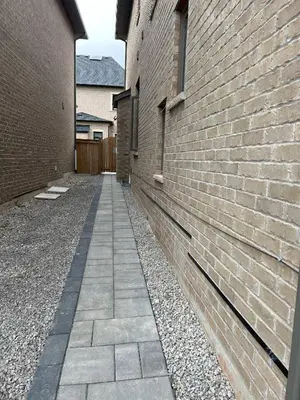 an alley between two buildings with a brick wall at Cozy basement suites Oakville in Oakville