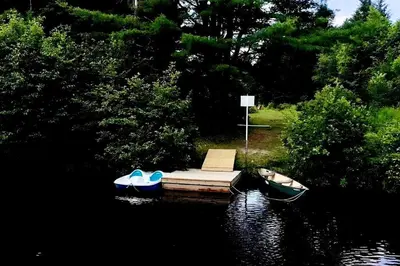 a small dock with two boats on the water at Lovely Muskoka Waterfront Cottage-Hot tub & Sauna! in Bracebridge