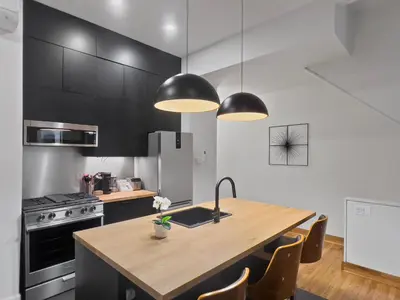 a kitchen with a wooden table and black cabinets at Historic Victorian with Deck and Parking in Toronto