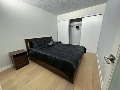 a bedroom with a bed with a black comforter at Downtown 2 bedroom Gem with Free Parking in Toronto