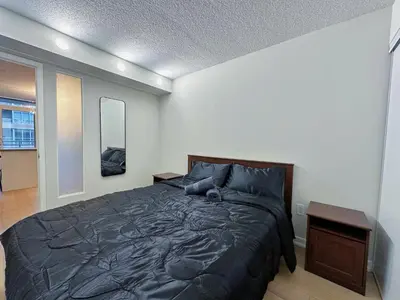 a bedroom with a bed with a black comforter at Downtown 2 bedroom Gem with Free Parking in Toronto
